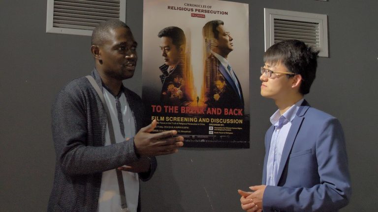  Mr. Totow Jean-Didier from Congolese Community in Greece exchanges views with a member of ACHRRF on the film To the Brink and Back. (Photo: Zhou Lei)