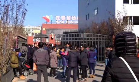 People stand in front of the main gate of the RYB New World Kindergarten in Beijing's Chaoyang district.