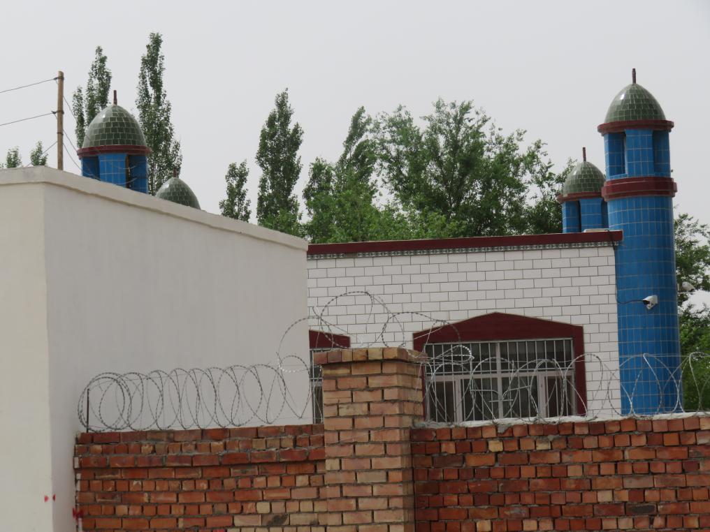 The crescent has been removed from the top of the Juma mosque in Shang Village’s No. 3 Production Team. Surveillance cameras on the mosque and razor wire on its wall are clearly visible.