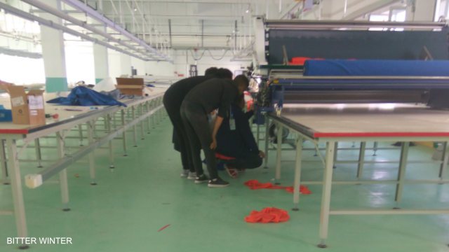 Workers adjust and test machines in a large factory.