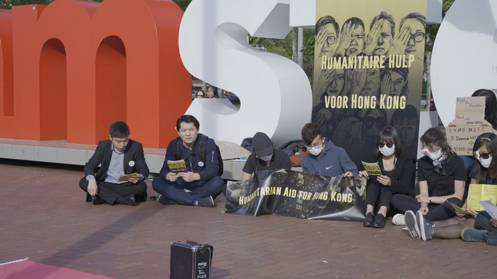 Attendants sitting in the square and singing “Glory to Hong Kong” 