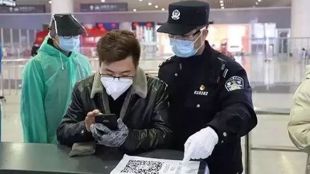 Police officers at a checkpoint in Hangzhou East Railway Station instruct passengers to use their mobile phones to scan health codes