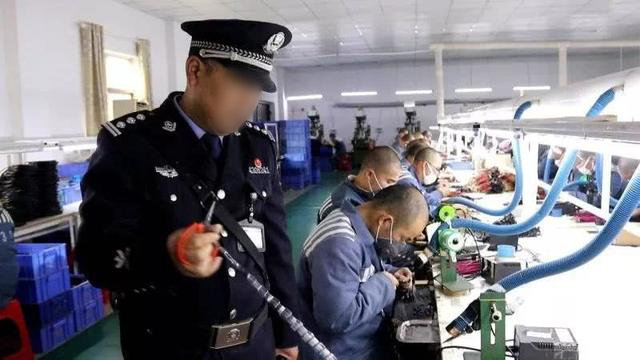 A guard supervises inmates working in a prison workshop