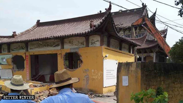 Government-hired workers are demolishing the Fuyuan Temple with an excavator.