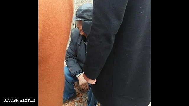 A villager cries in grief after his house was forcibly demolished.