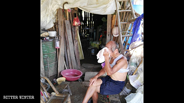 A man in his 80s sits outside his shed.