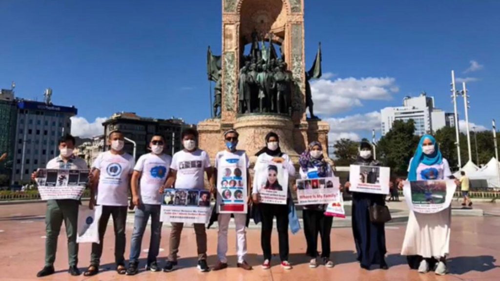 Uyghurs wearing T-shirts with images of missing relatives pose for a photo in front of the Republic Monument on Taksim Square in Istanbul, Aug. 17, 2020