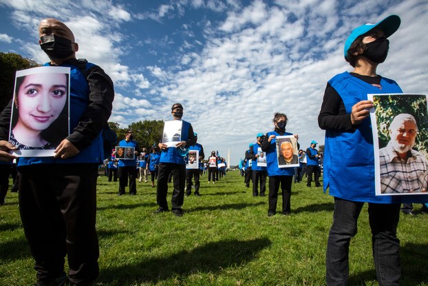 Uyghur protesters hold up pictures of their family members during "Resist CCP: Global Day of Action" in front of the Capitol Reflecting Pool in Washington D.C., Oct. 1, 2020.